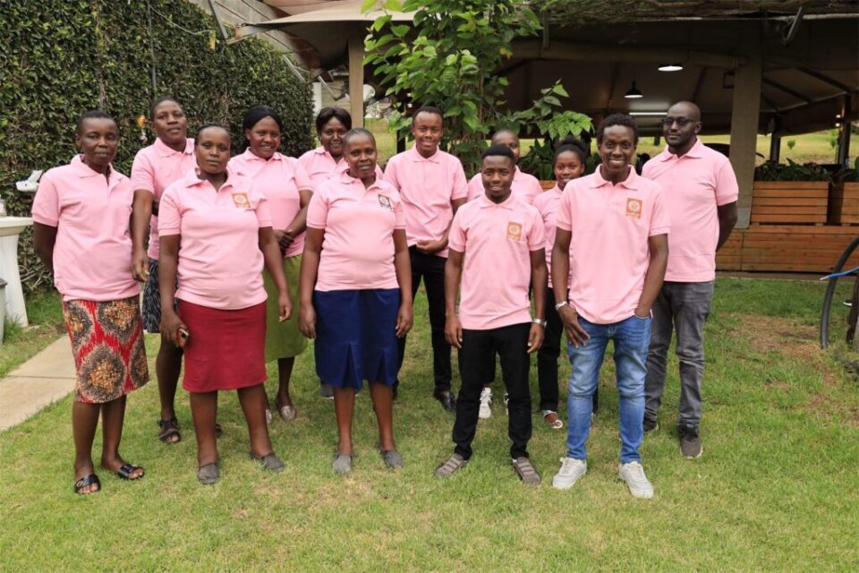The Mambo Leo team in pink polo shirts standing together on a lawn in Kenya