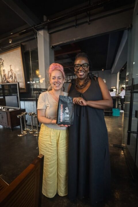 Erin holding a bag of Mambo Leo coffee with a member of the Association of Women in Coffee Industry (Kenya)